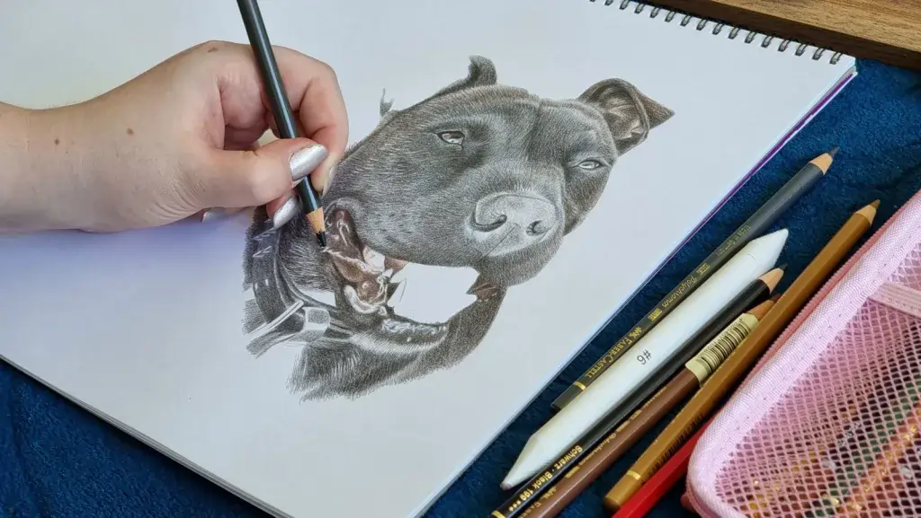 A close-up image of the artist working on a commissioned pet drawing